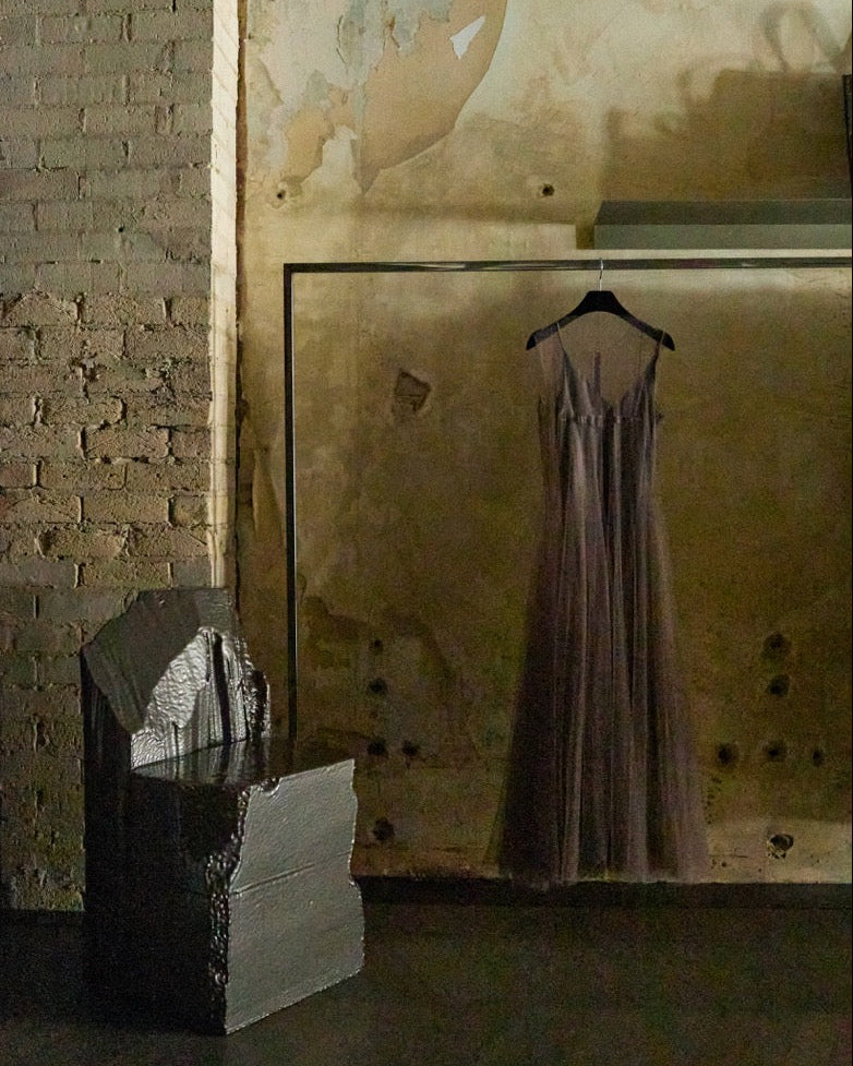 Marc Le Bihan tulle dress hanging on a clothes rack against a textured wall with an avant-garde designer chair.